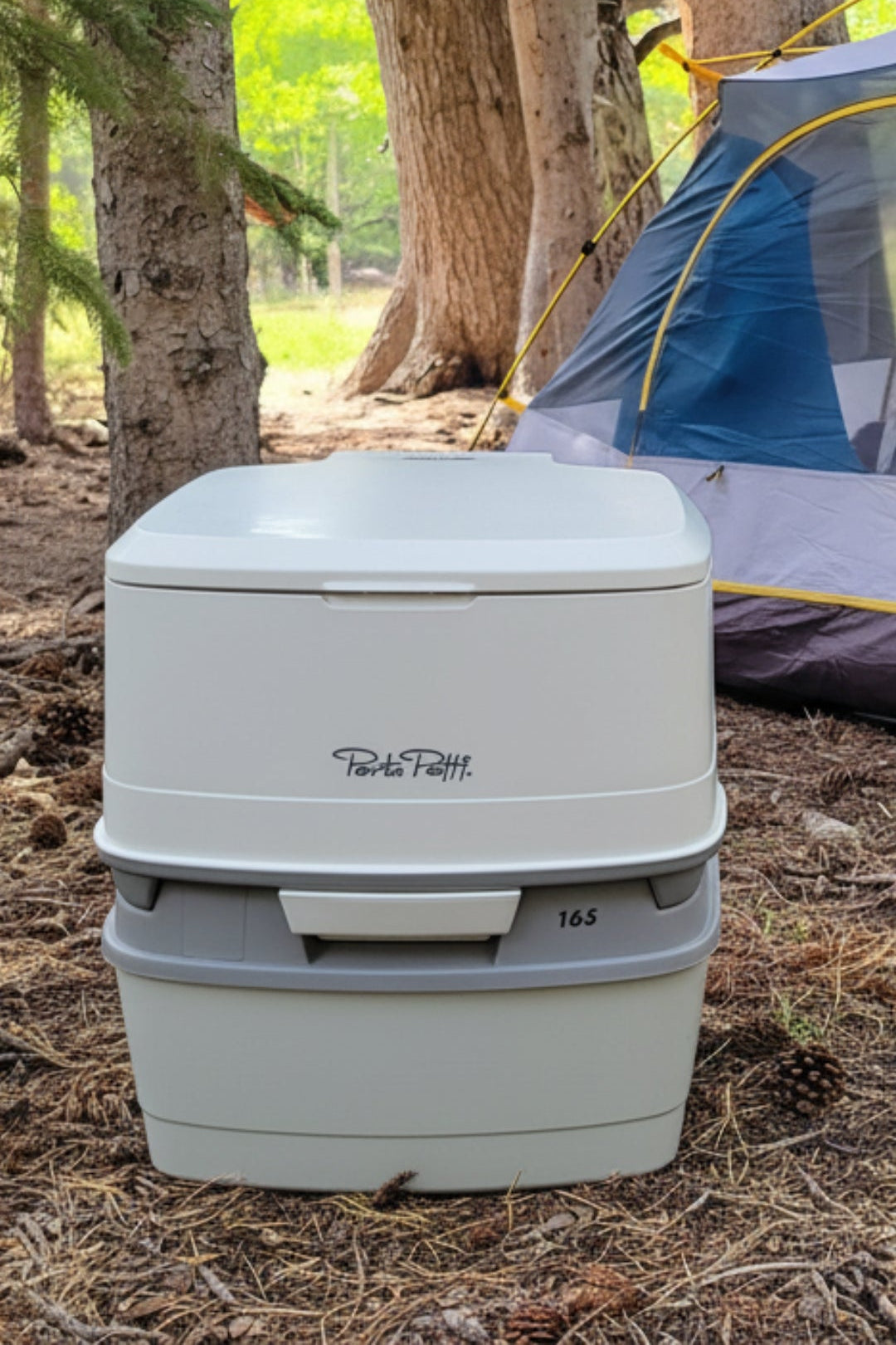 Portable toilet on a camping site with trees and a tent in the background