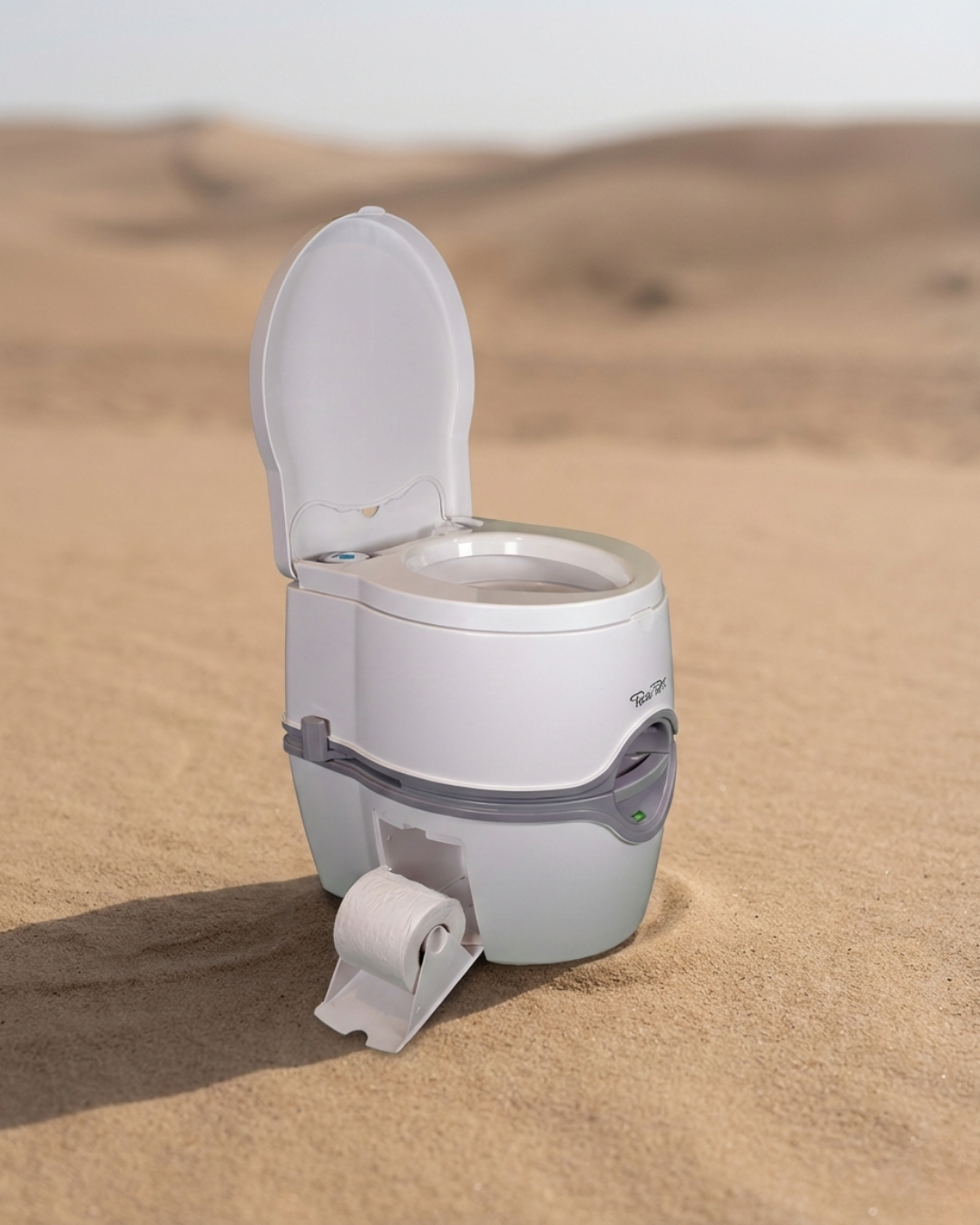 Portable toilet in the desert with sand dunes in the background